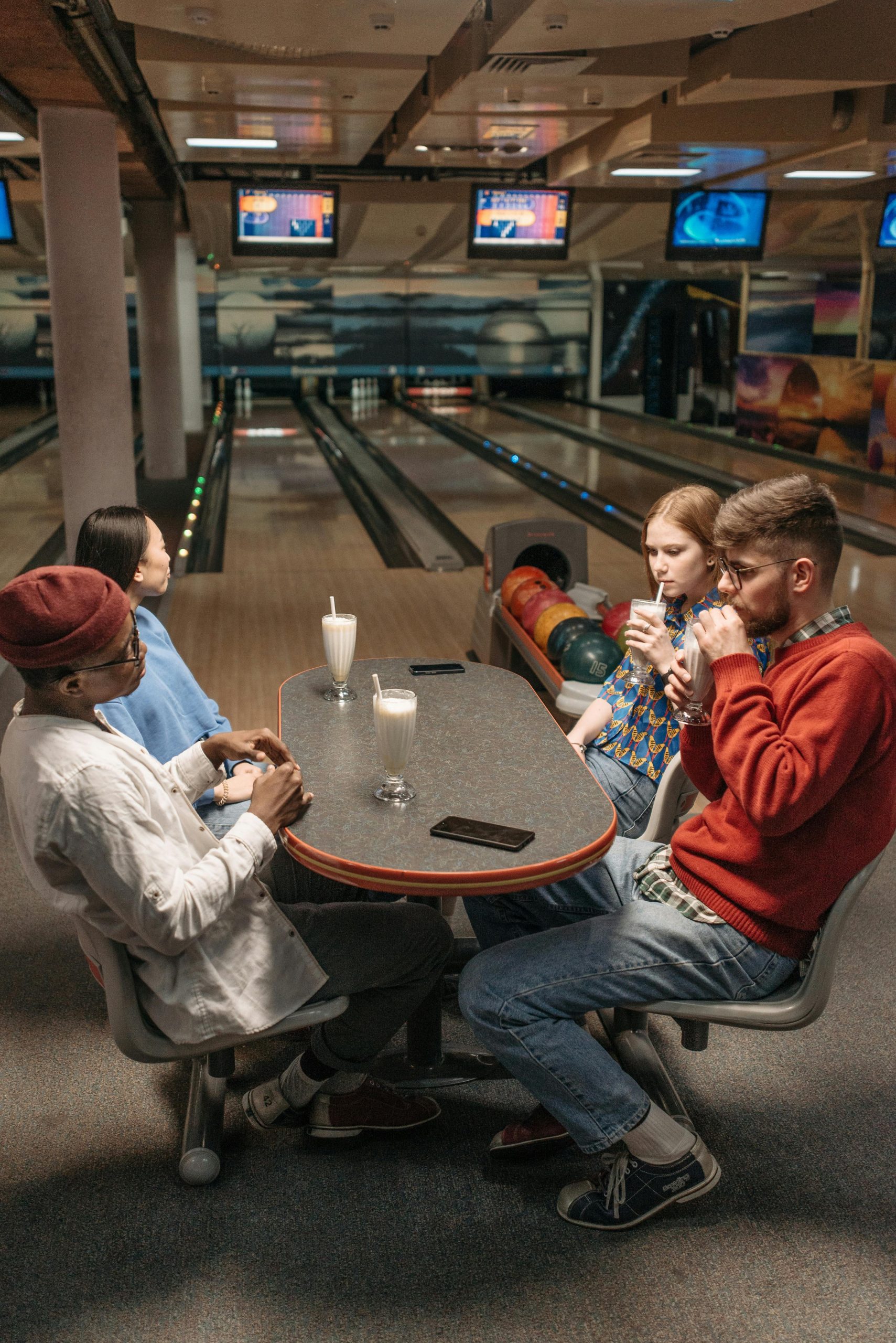 Group of friends having a fun time with drinks at an indoor bowling alley.